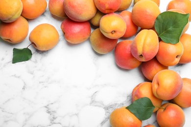 Many fresh ripe apricots on white marble table, flat lay. Space for text