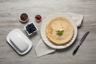 Photo of Delicious crepes with different products served on white wooden table, flat lay