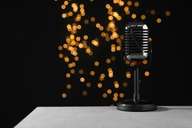 Photo of Vintage microphone on table against black background with blurred lights, space for text. Sound recording and reinforcement