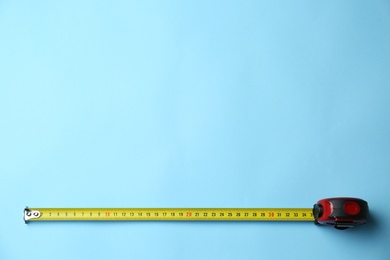 Photo of Tape measure on light blue background, top view. Space for text
