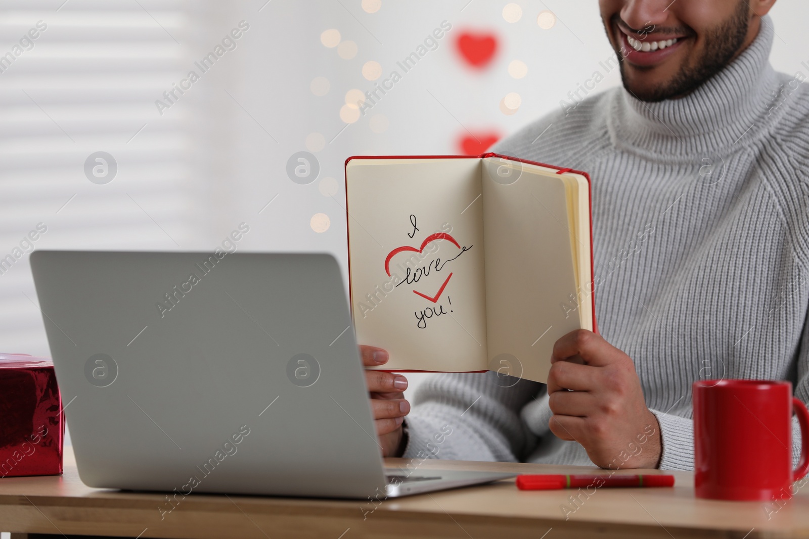 Photo of Valentine's day celebration in long distance relationship. Man having video chat with his girlfriend via laptop, closeup