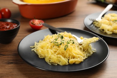 Photo of Tasty spaghetti squash with thyme and cheese served on wooden table, closeup