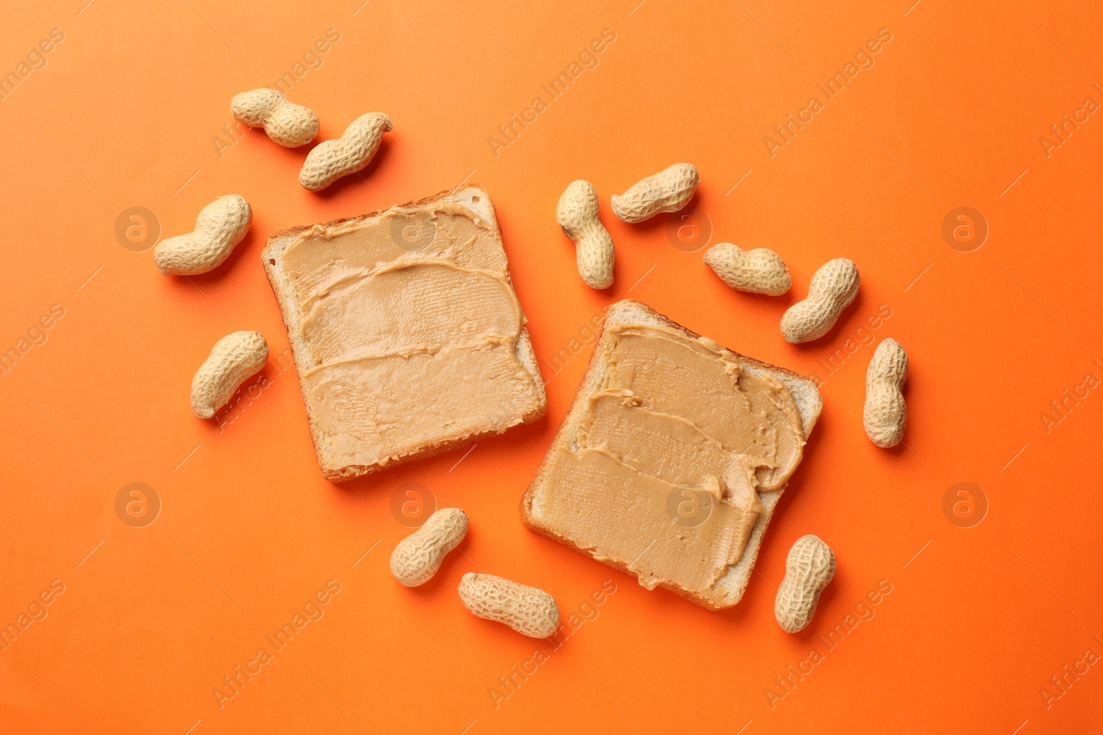 Photo of Tasty peanut butter sandwiches and peanuts on orange background, flat lay