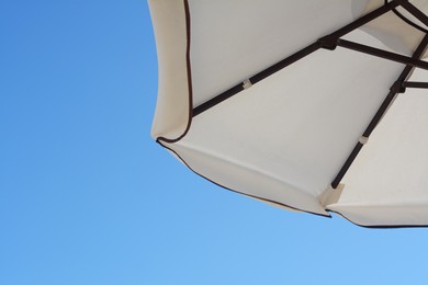 Photo of Beautiful white beach umbrella against blue sky. Space for text