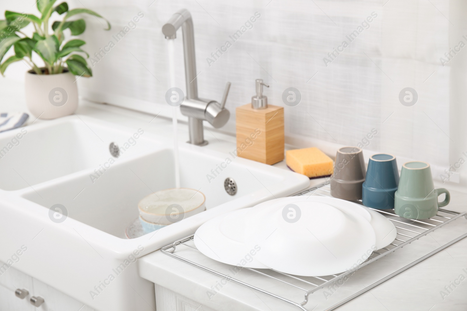 Photo of Drying rack with clean dishes near sink in stylish kitchen