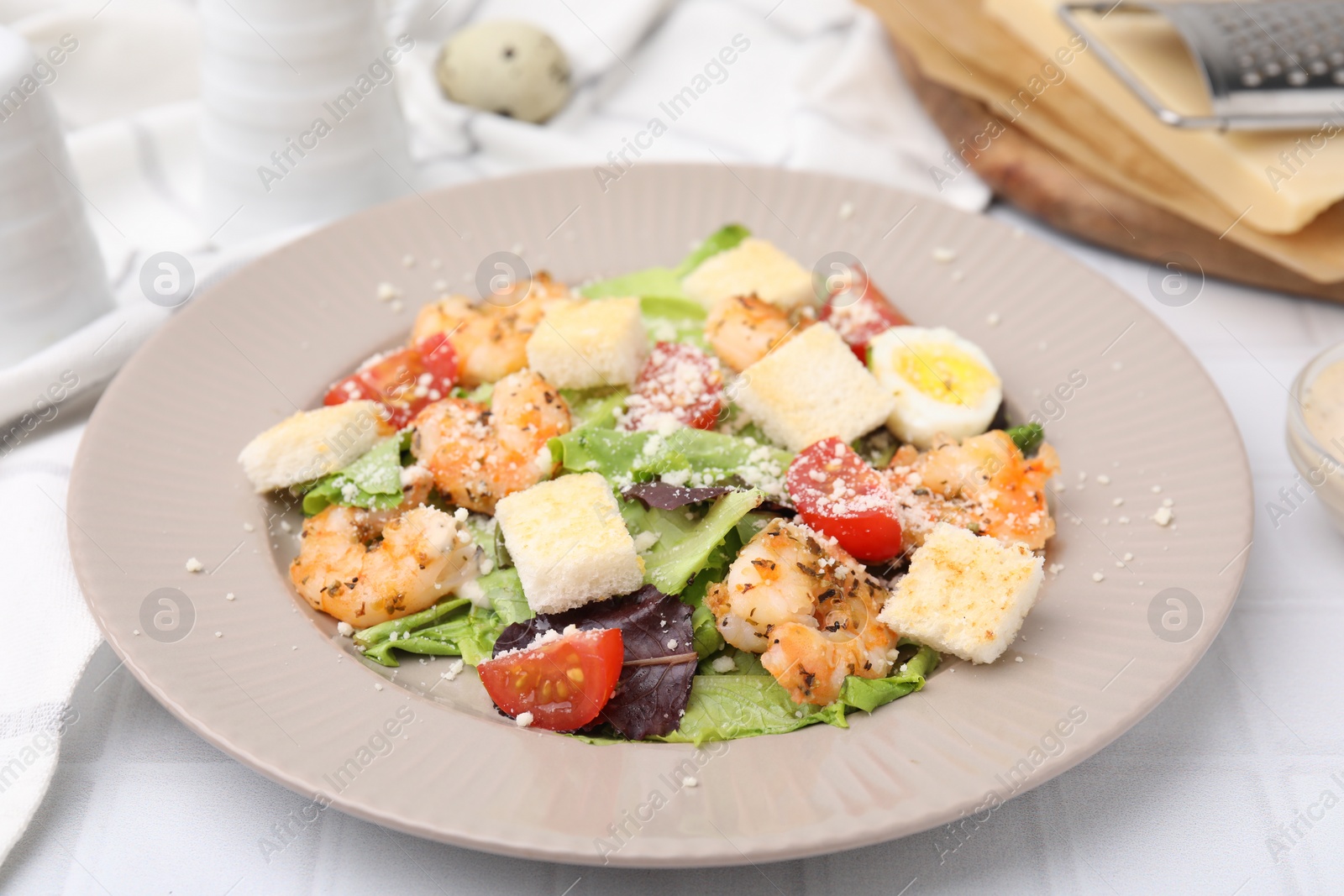 Photo of Delicious Caesar salad with shrimps on white table, closeup