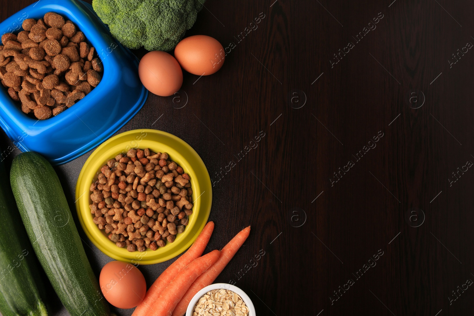 Photo of Dry pet food and products on wooden background, flat lay. Space for text