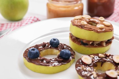 Photo of Fresh apples with nut butters, blueberries and nuts on plate, closeup