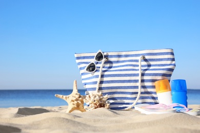 Set with stylish beach accessories on sand near sea