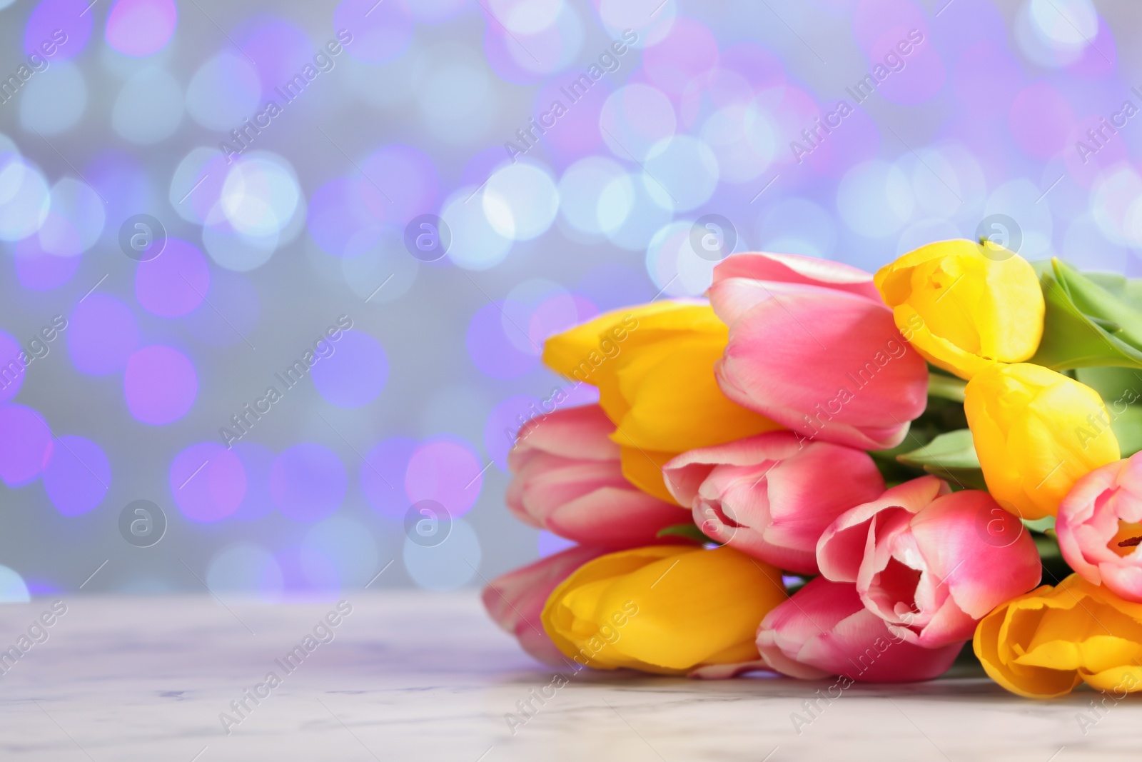 Photo of Bouquet of flowers on table against blurred lights, space for text