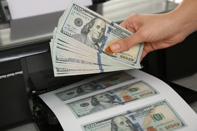 Photo of Counterfeiter printing dollar banknotes at table, closeup. Fake money concept