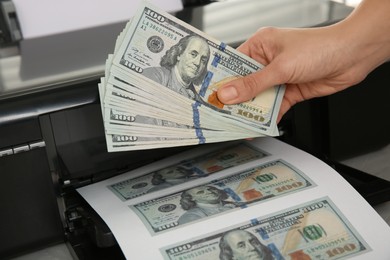 Counterfeiter printing dollar banknotes at table, closeup. Fake money concept