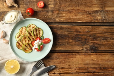 Photo of Flat lay composition with delicious grilled zucchini slices on wooden table, space for text