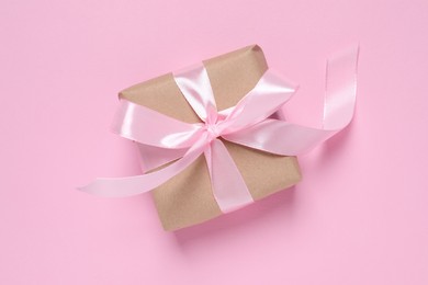 Beautiful gift box with bow on pink background, top view