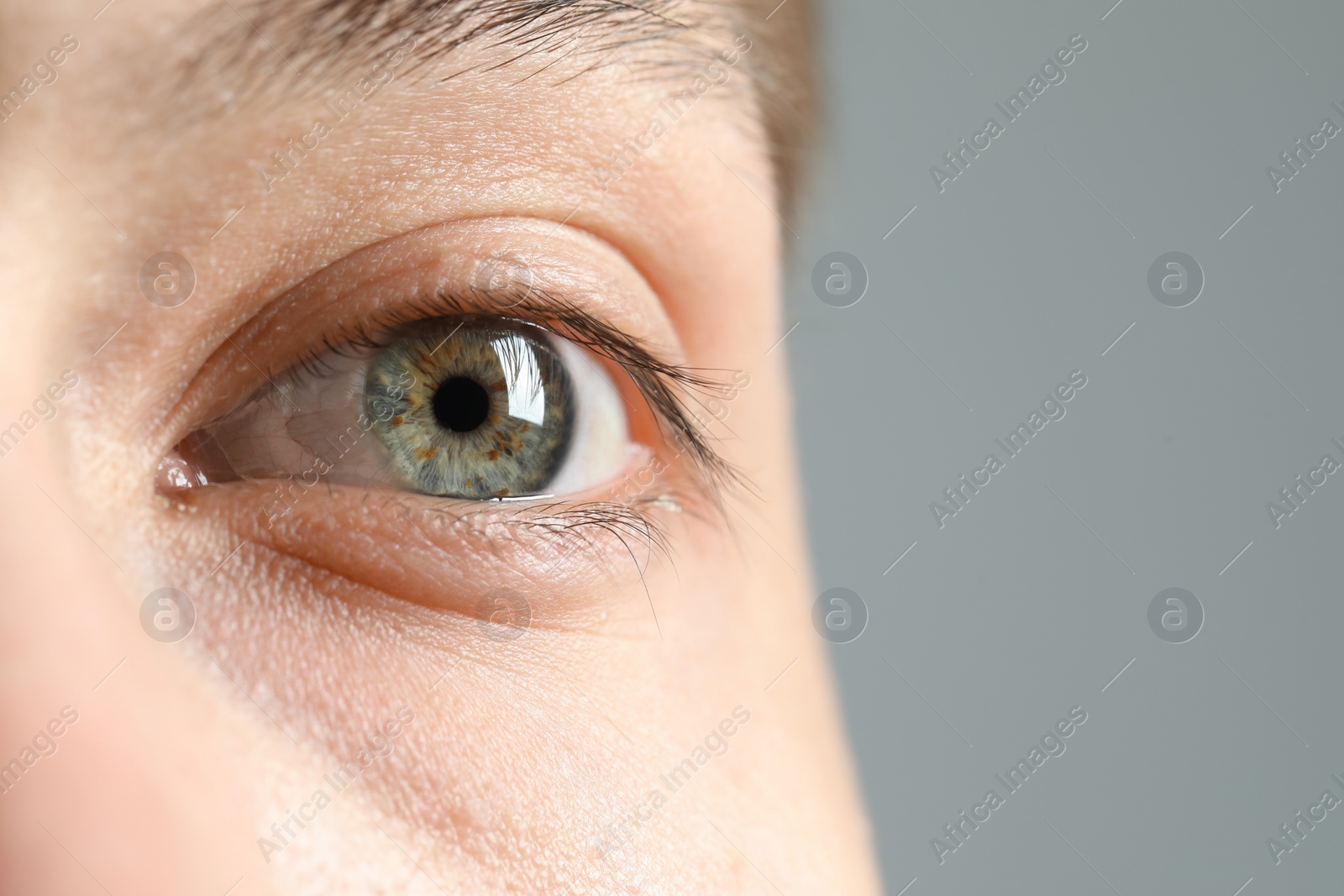 Photo of Perfect vision. Man with beautiful eyes on grey background, closeup. Space for text