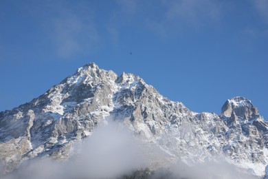 Photo of Picturesque landscape of high mountains covered with thick mist under blue sky
