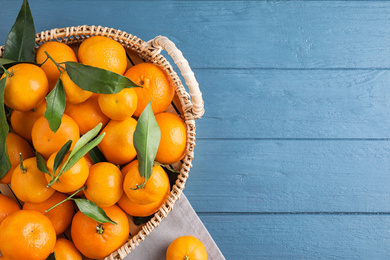Photo of Fresh ripe tangerines on blue wooden table, flat lay. Space for text