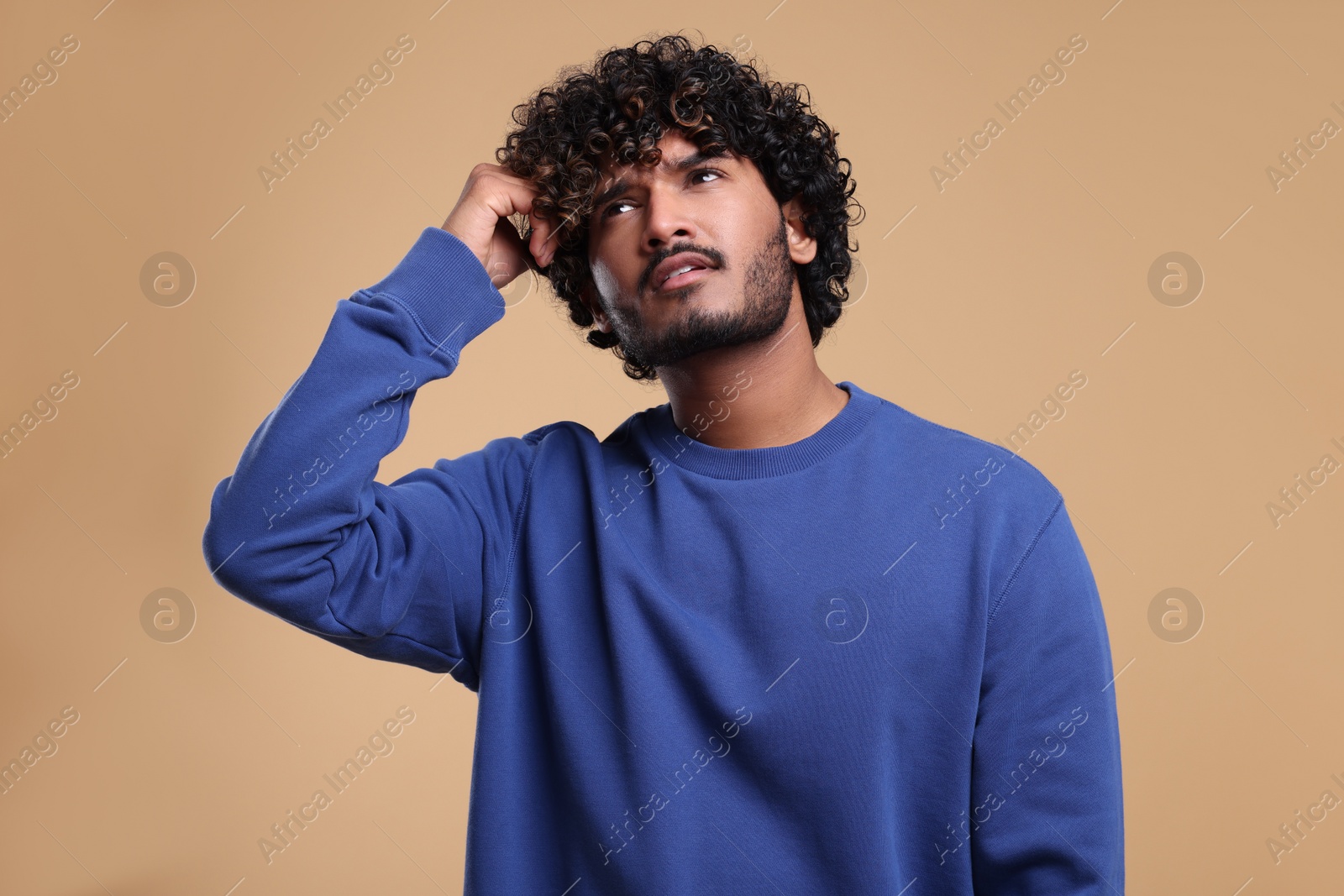 Photo of Handsome young thoughtful man on beige background