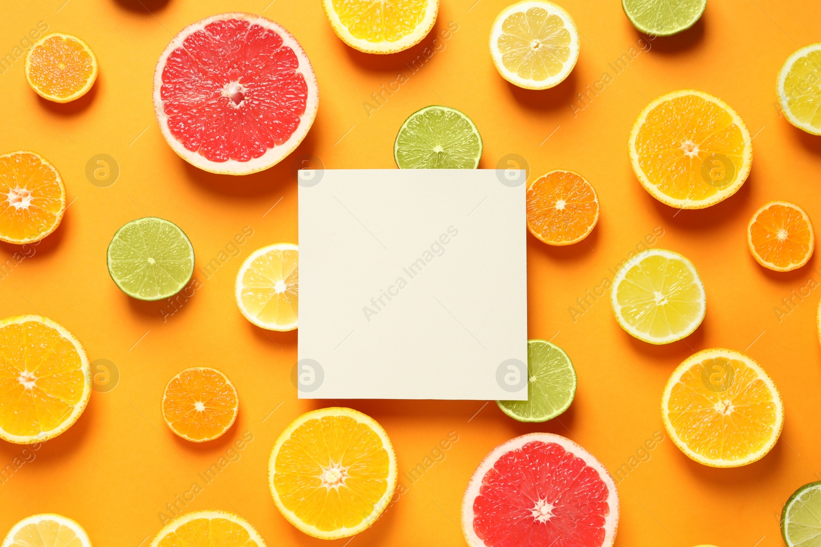 Photo of Fresh citrus fruits and blank card on color background, flat lay. Space for text