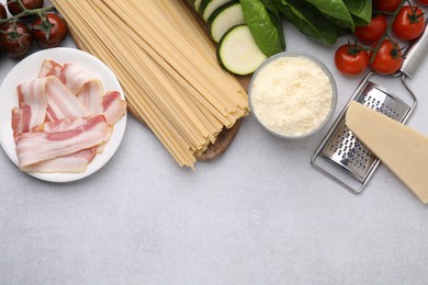 Photo of Raw pasta and fresh ingredients on light grey table, flat lay. Space for text