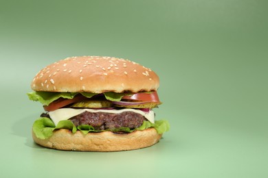 Photo of Burger with delicious patty on green background. Space for text