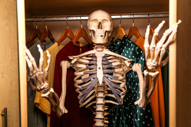 Artificial human skeleton model among clothes in wardrobe