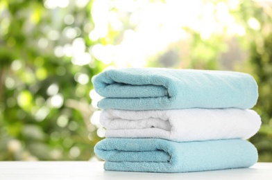 Stack of clean soft towels on table against blurred background. Space for text