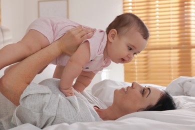 Photo of Happy woman with her little baby on bed at home