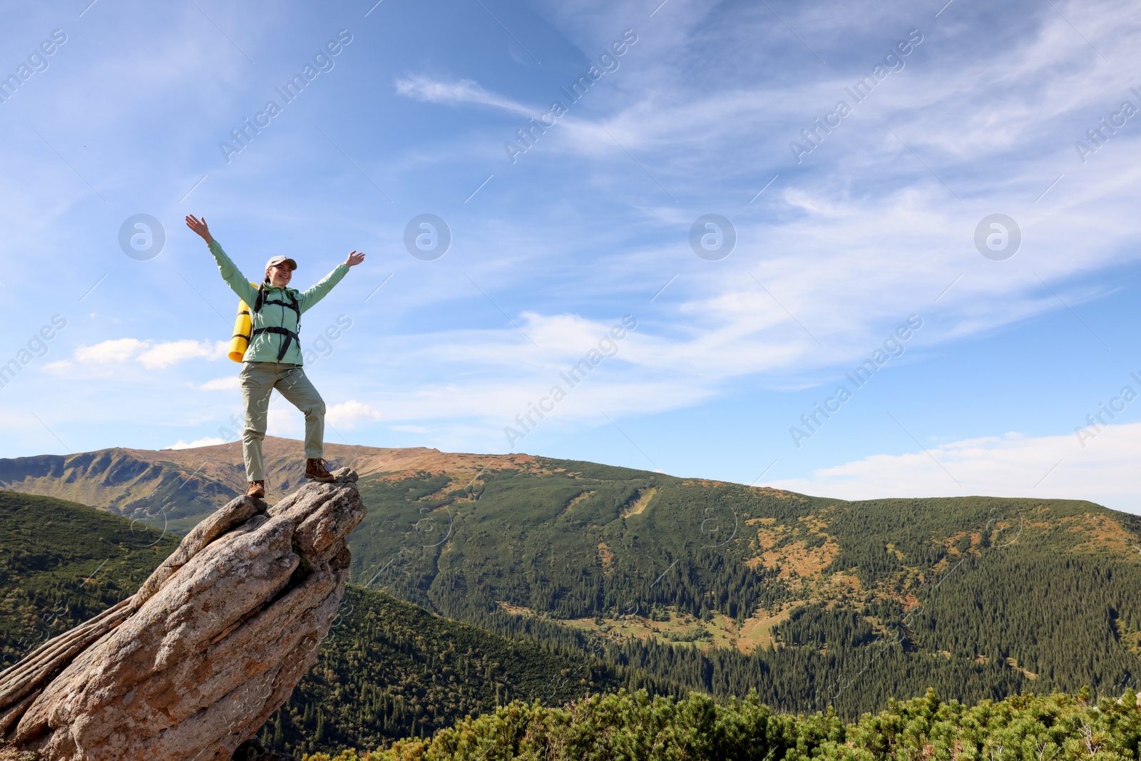 Photo of Young woman with backpack on rocky peak in mountains. Space for text