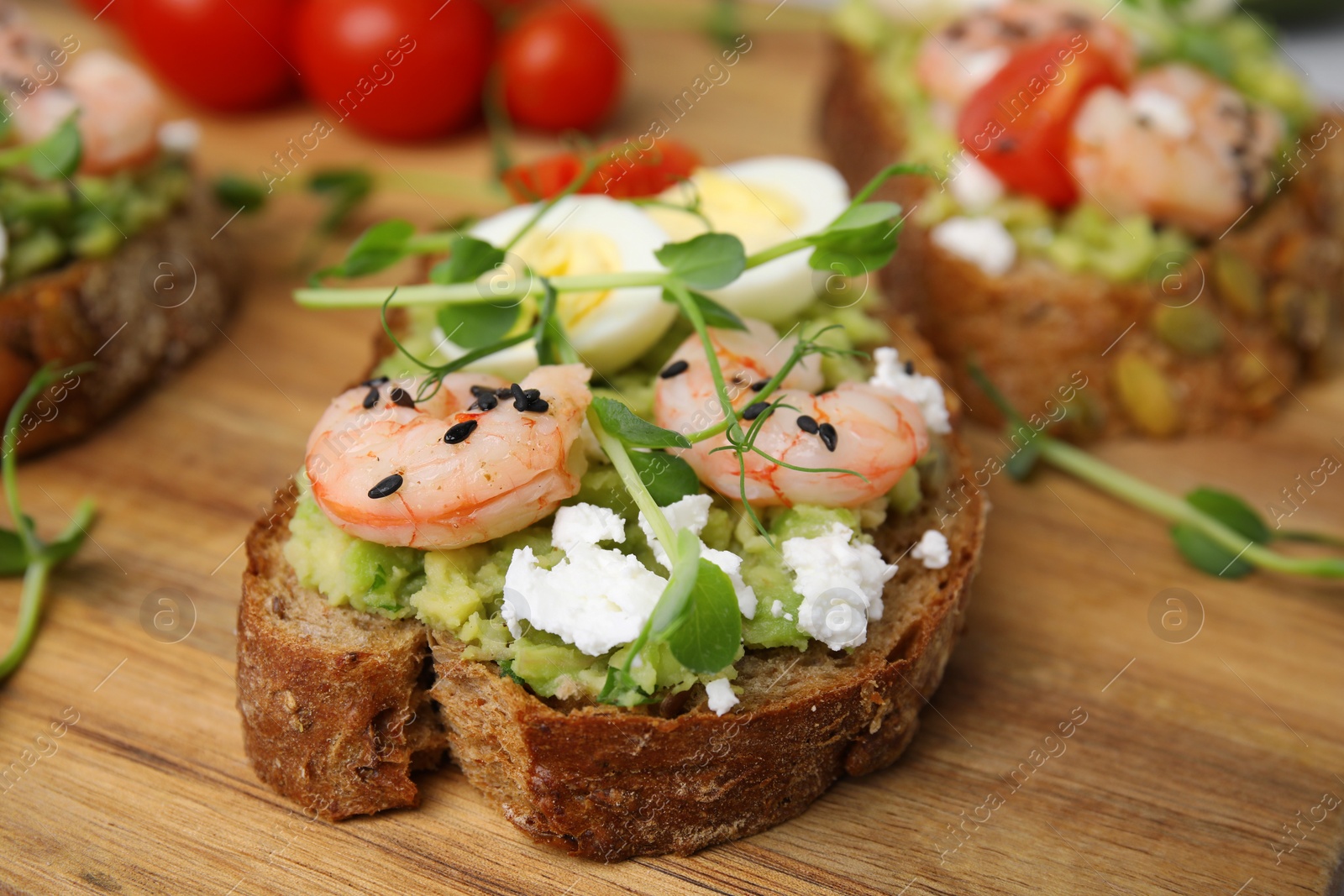 Photo of Delicious sandwiches with guacamole, shrimps and microgreens on wooden table, closeup