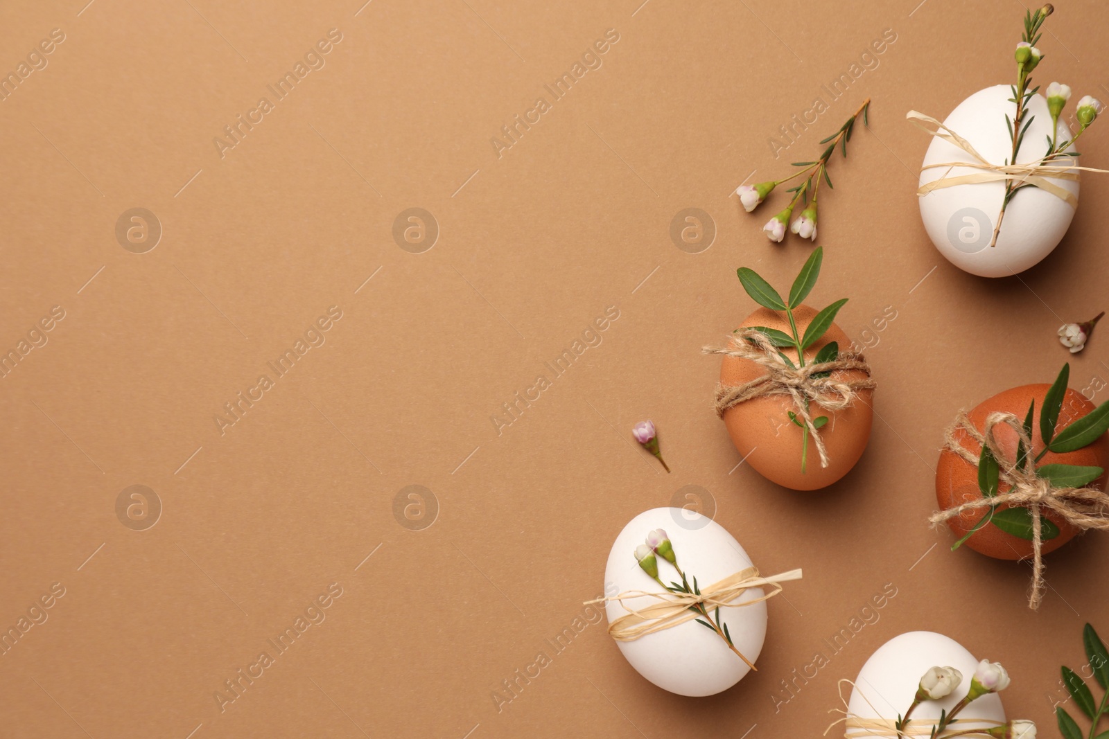 Photo of Happy Easter. Festive composition with eggs and floral decor on brown background, flat lay. Space for text.