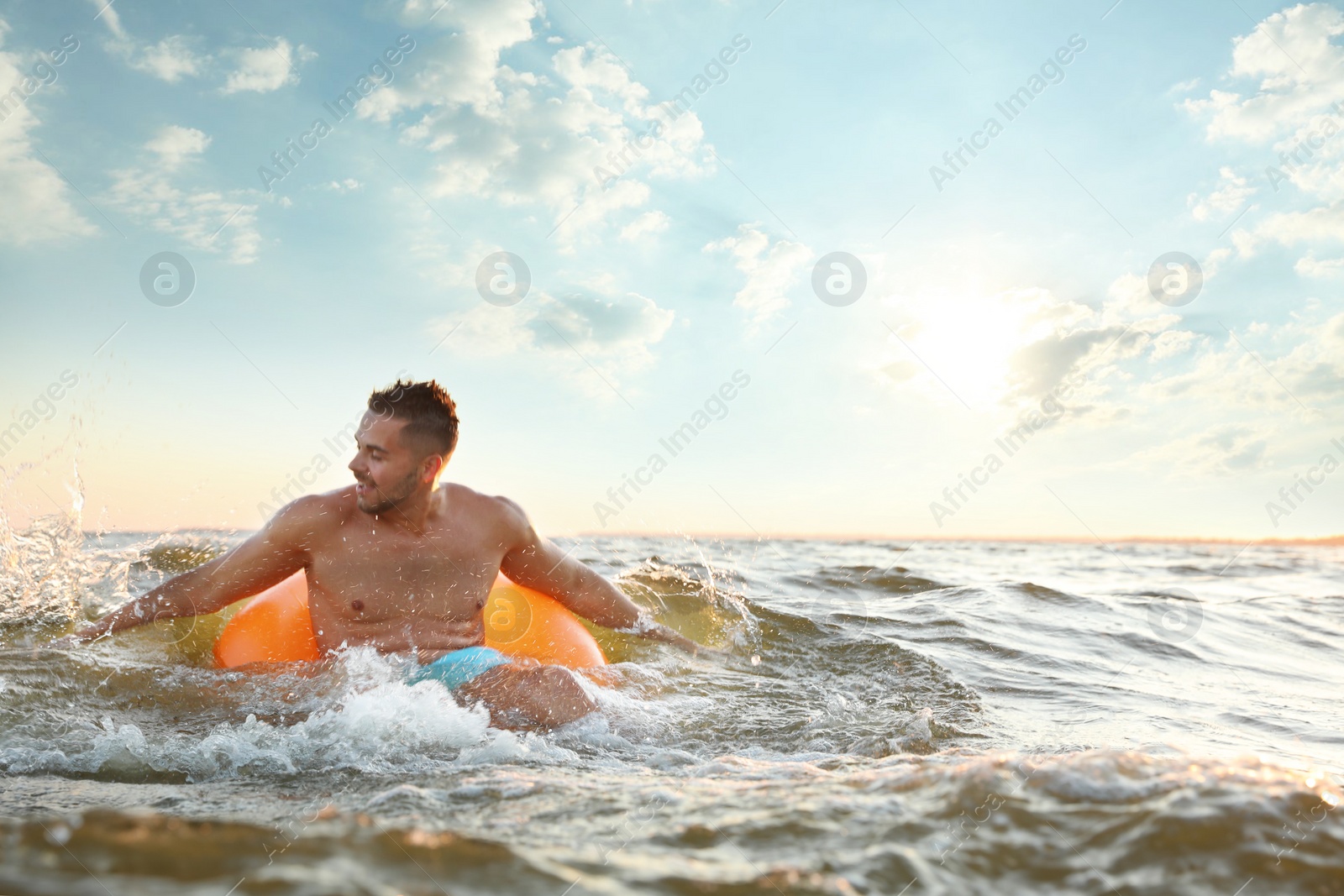 Photo of Happy young man on inflatable ring in water