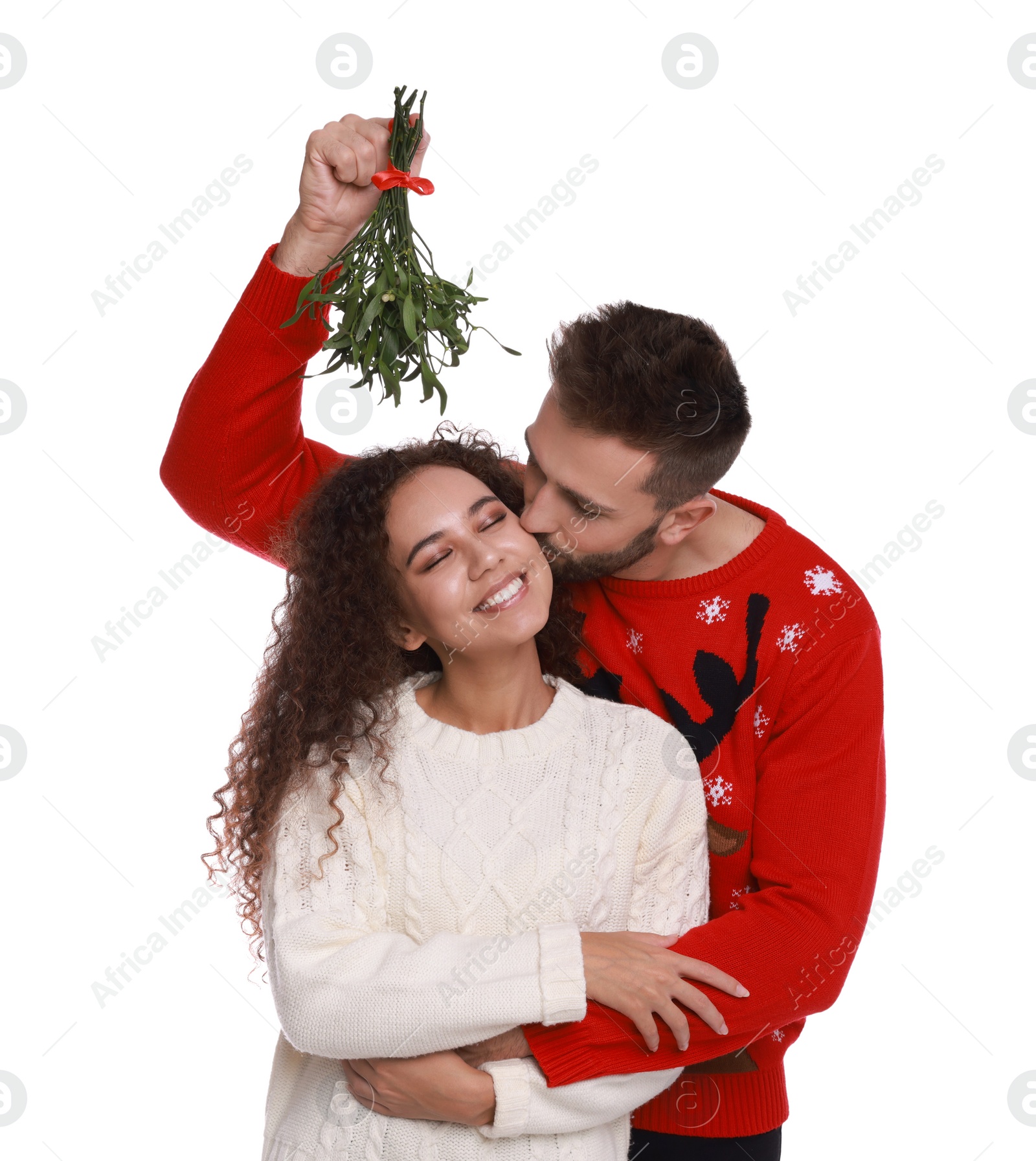 Photo of Happy man kissing his girlfriend under mistletoe bunch on white background