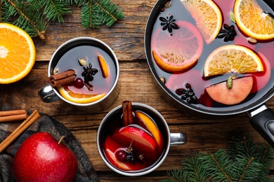 Delicious mulled wine and ingredients on wooden table, flat lay