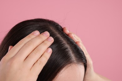 Photo of Woman examining her hair and scalp on pink background, closeup. Space for text