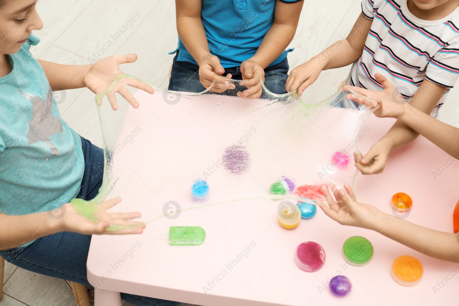 Photo of Children playing with slime at table indoors, closeup