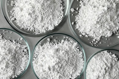 Photo of Petri dishes with calcium carbonate powder on grey table, flat lay