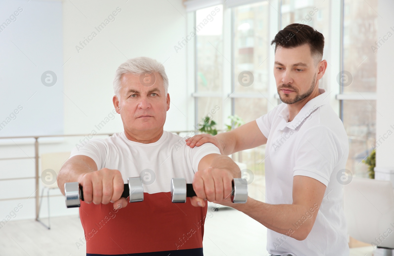 Photo of Young physiotherapist working with senior patient in clinic