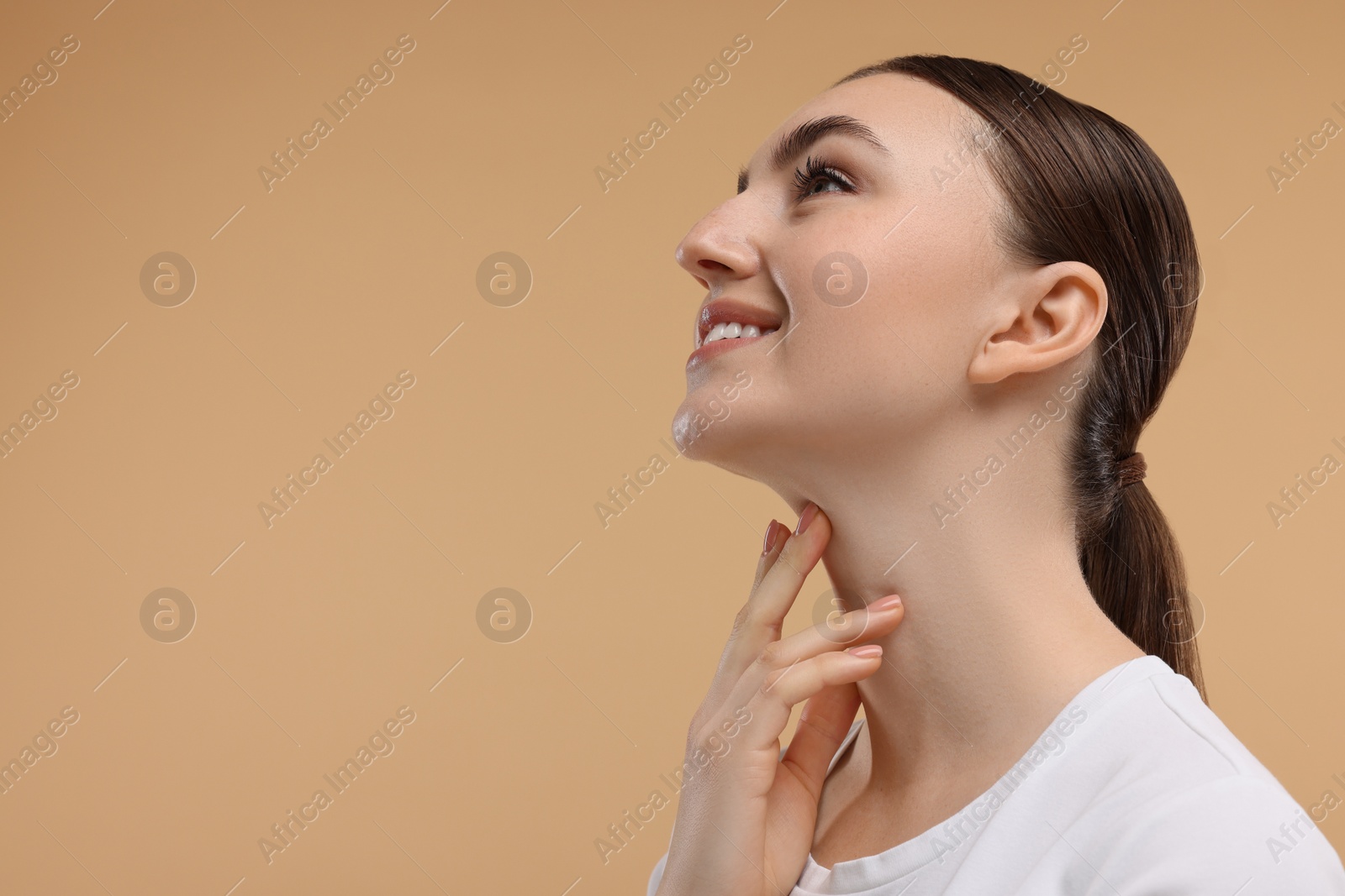 Photo of Smiling woman touching her chin on beige background. Space for text