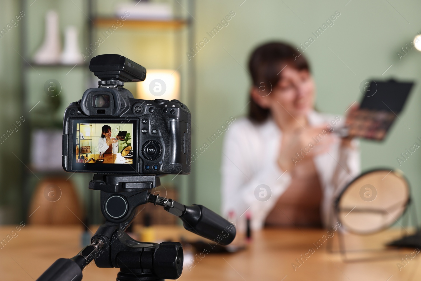 Photo of Beauty blogger recording video while showing eyeshadow palette at home, focus on camera