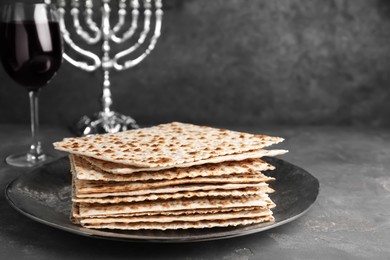 Photo of Stack of traditional matzos near red wine on grey table