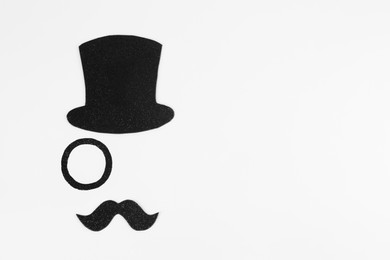 Photo of Fake mustache, hat and monocle on white background, top view. Space for text