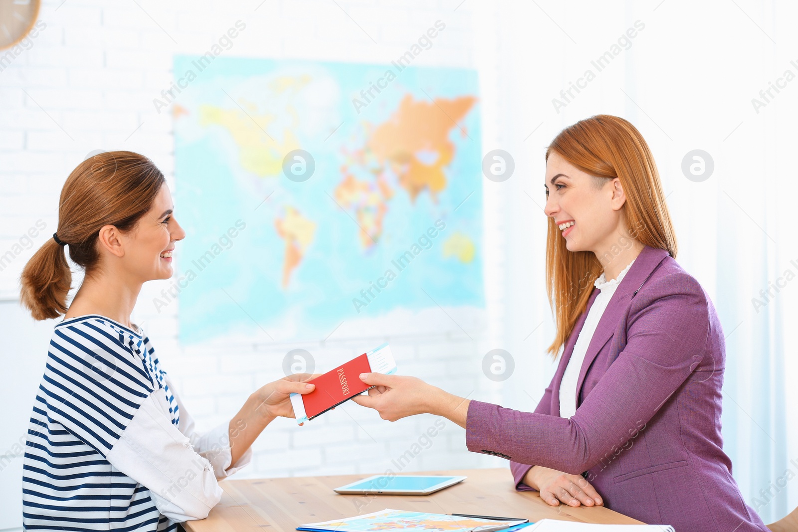 Photo of Female manager giving passport with ticket to client in travel agency