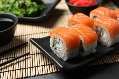 Photo of Tasty sushi rolls served on black table, closeup