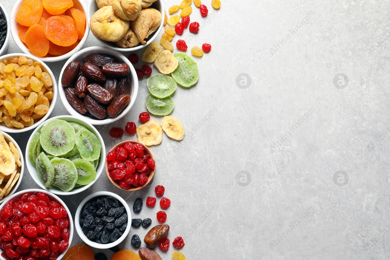 Photo of Bowls of different dried fruits on grey background, top view with space for text. Healthy food