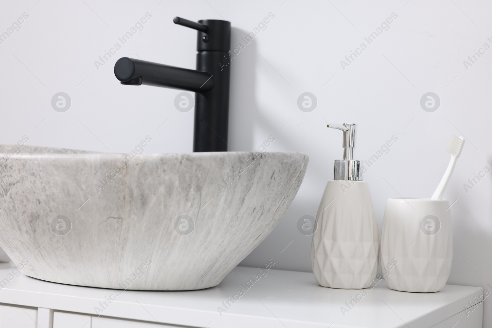 Photo of Different bath accessories and personal care products near sink on bathroom vanity