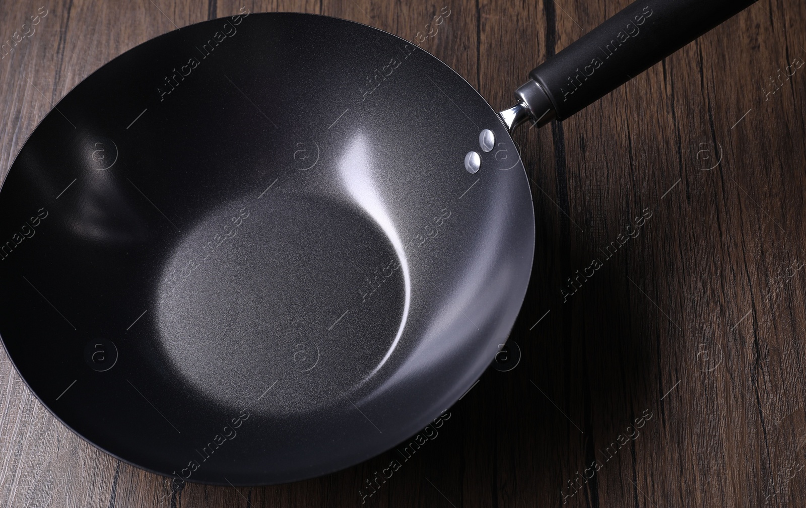 Photo of Empty iron wok on wooden table, closeup. Chinese cookware