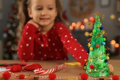 Photo of Cute little child with beautiful Christmas decor at home, focus on paper tree