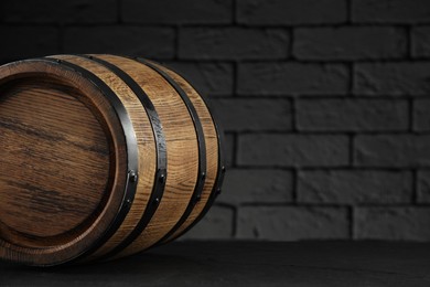 Photo of One wooden barrel on table near brick wall, closeup. Space for text