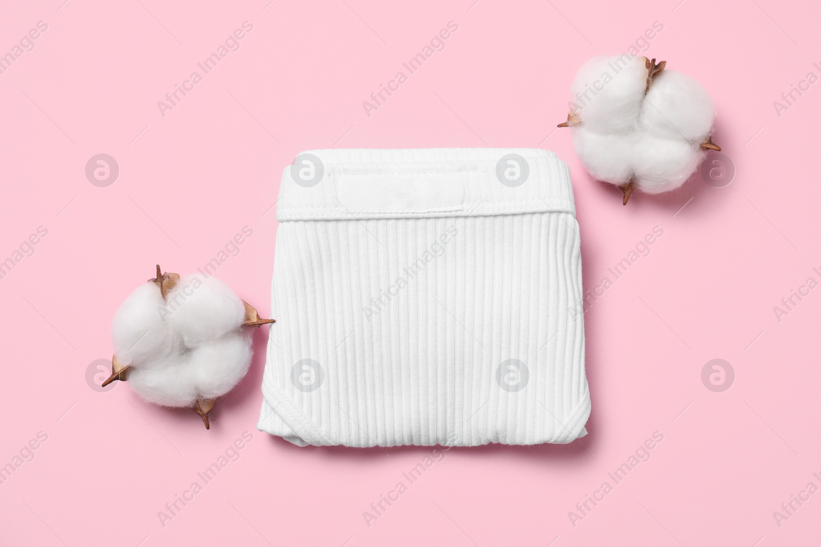 Photo of Stylish folded women's underwear and cotton flowers on pink background, flat lay